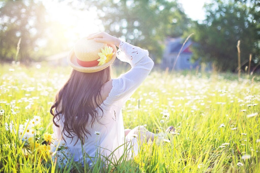 woman sitting in field of flowers in sunshine