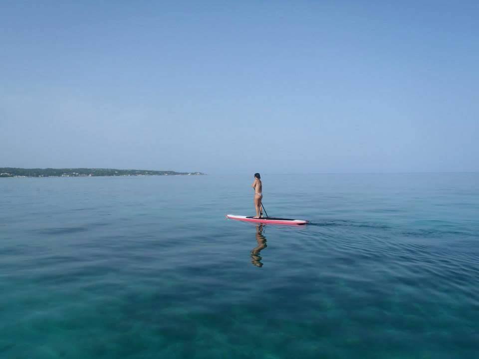 Woman paddle boarding on flat ocean